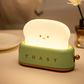 Finger pressing brass lever on green toaster night light with three step-by-step thumbnails showing the press-to-toggle action