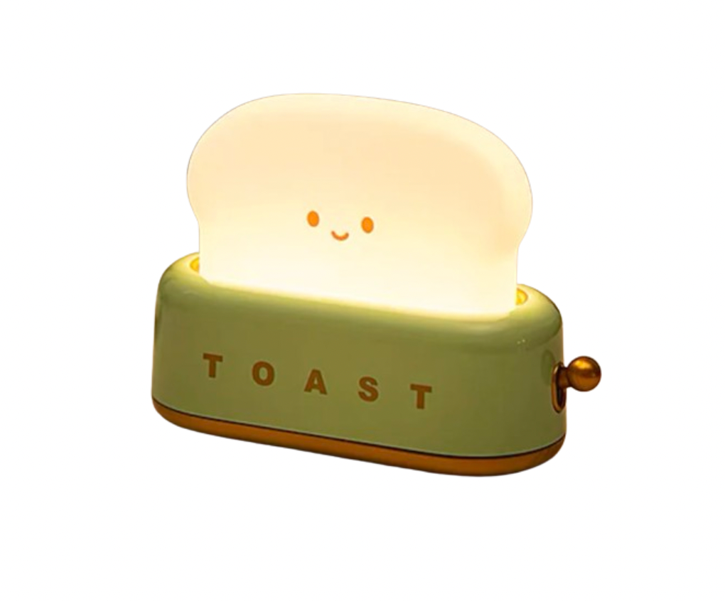 Green toaster-shaped night light with smiling toast slice glowing warm white and TOAST text on base, side angle on white background